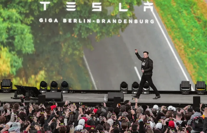 A high-resolution outdoor LED video wall screen showcasing dynamic visuals at a Tesla event, capturing the attention of the audience